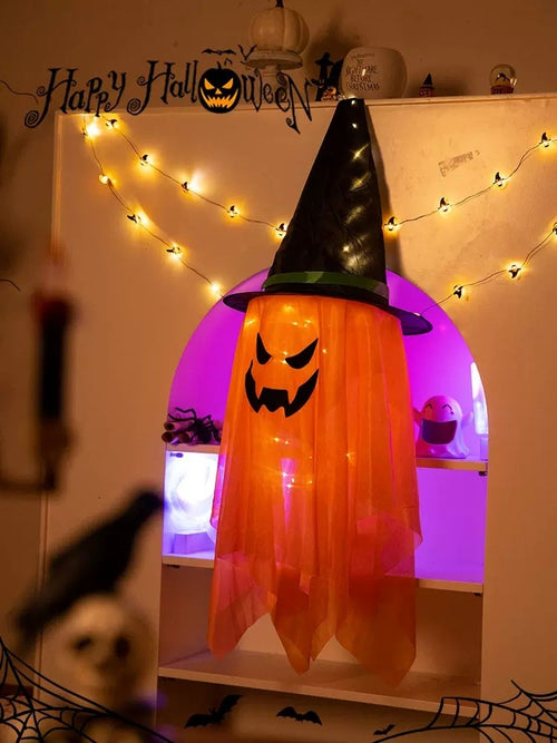 Orange hanging witch decoration with its lights on; background lights are not included.